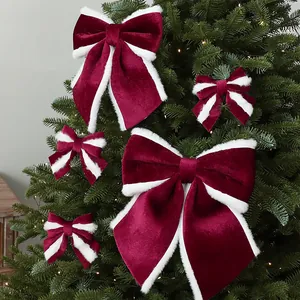 Bourgondische fluwelen kerststrikken met witte bontrand op een groene kerstboom
