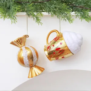 Primo piano di decorazioni natalizie a forma di caramella dorata e tazza su un pino
