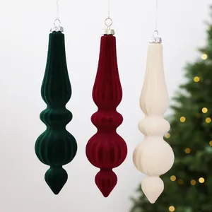 Gros plan de trois suspensions de Noël en velours de couleur verte, rouge et crème