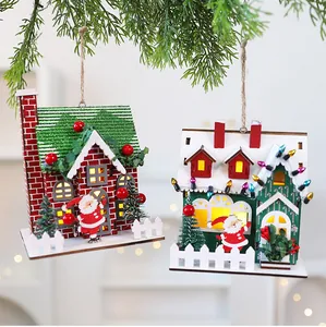 Detailed view of festive Christmas wooden cabin ornaments hanging from green pine branches.