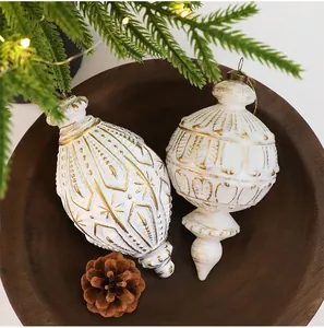 Detaillierte Nahaufnahme von weißen und goldenen Vintage-Weihnachtsanhängern in einer Holzschale