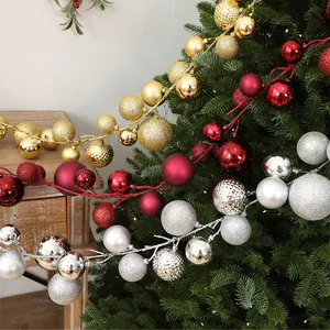 Detailansicht festlicher 1,9m Weihnachtskugel-Girlanden an Tannenbaum und Holztisch.