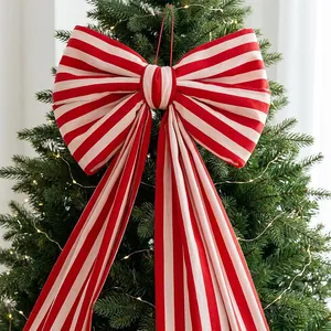 Detail of a large red and white striped fabric bow decoration on a lit Christmas tree