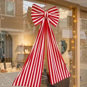 Detailed view of a large red and white striped Christmas bow hanging on a shop window