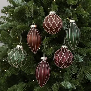 Close-up of matte green and burgundy Christmas ornaments with glitter details on a tree.