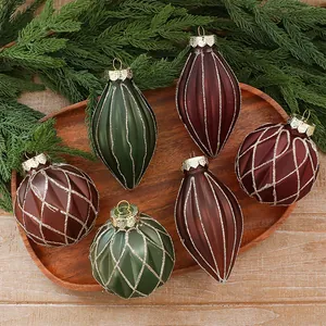 Elegant matte PET Christmas ornaments in green and burgundy with glitter details on wood.