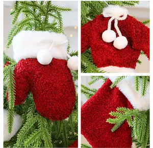 Close-up van rode fleece kerstversieringen zoals mini-truien en sokken hangend aan een boom.