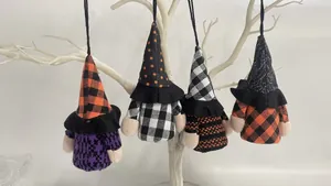 Macro view of four hanging Halloween gnome plushies on a white decorative branch.