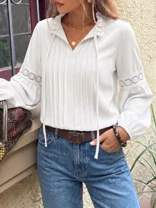 Vista detallada de elegante blusa blanca con cuello de encaje y mangas de farol en modelo