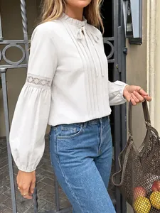 Detalle de elegante blusa gris con cuello de volantes y mangas de encaje huecas.