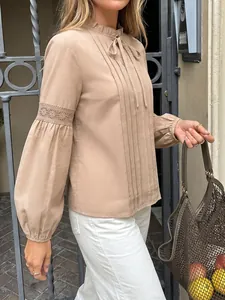 Elegante blusa beige con lazo al cuello, cuello de volantes y detalles de encaje en mangas