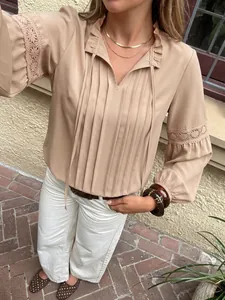 Elegante blusa plisada beige con mangas de encaje y cuello con volantes para uso casual.