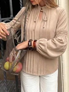 Detalle de blusa beige con cuello de volantes y mangas de encaje
