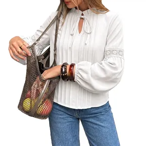 Elegante blusa blanca de manga larga con detalles de encaje y cuello con lazada.