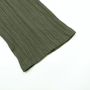 Macro view showing the fine crinkle texture and hem detail of olive green jumpsuit.