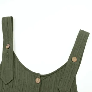 Close-up detail of olive green textured jumpsuit shoulder straps and wooden buttons