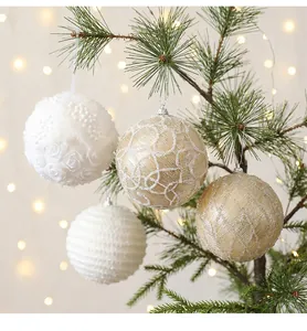 Nahaufnahme von 10 cm großen Weihnachtskugeln mit Pailletten und Blumen auf einem Tannenzweig