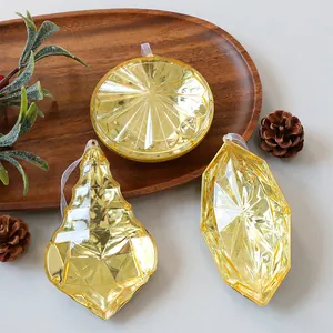 Detalle de adornos navideños de gema acrílica amarilla traslúcida en una bandeja de madera