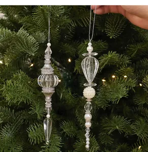 Transparenter Christbaumschmuck aus Acryl mit Perlen an einem grünen Tannenzweig