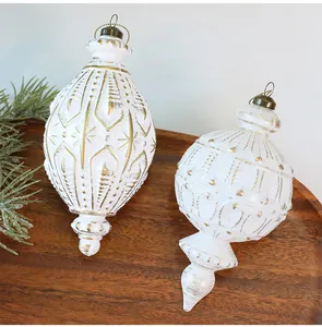 Weiße und goldene Vintage-Weihnachtskugeln auf einem Holztablett mit grünen Tannenzweigen