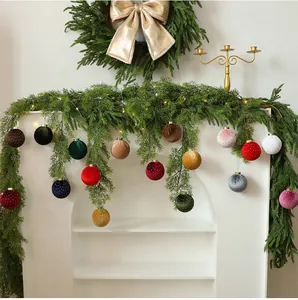 Eleganti palline di Natale in velluto appese a una ghirlanda festiva per decorare la casa.