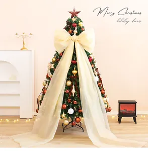 Grote crème mesh strik op een versierde kerstboom voor feestdecoratie.