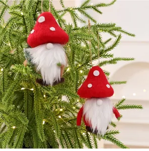 Adorable wool felt Christmas gnomes with mushroom hats hanging on a lit tree