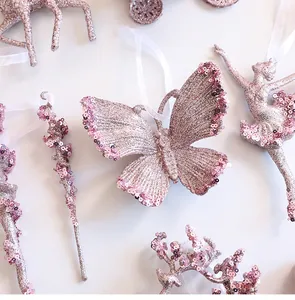 Close-up of pink glittery butterfly Christmas ornament with shimmering sequins on white base.