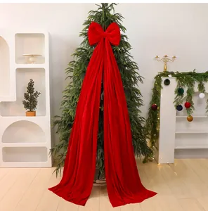 Detail of large red velvet Christmas tree bow with long streamers in a festive room.