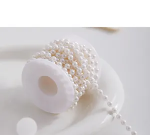 Close-up detail of white faux pearl bead string neatly wrapped on a plastic spool for DIY crafting.