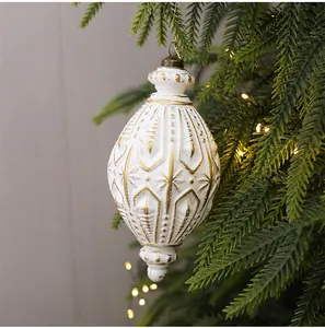 Nahaufnahme eines antiken weiß-goldenen Weihnachtsbaumanhängers in Zapfenform.
