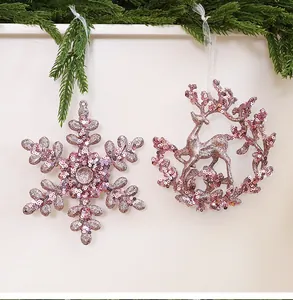 Detail of pink glittery snowflake and reindeer Christmas ornaments with green pine decor