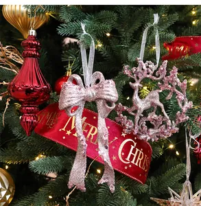 Close-up of pink glitter bow and reindeer ornaments on a decorated Christmas tree