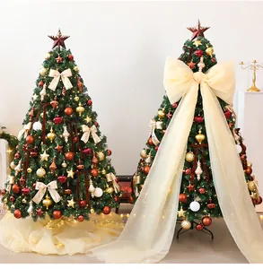 Detail van twee versierde PVC kerstbomen met een grote crème mesh strik decoratie.