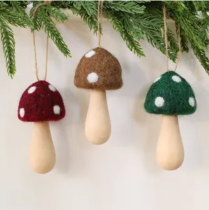 Handmade felt mushroom Christmas ornaments with wooden stems hanging from pine branch