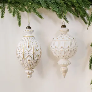 Paar antike weiß-goldene Weihnachtskugeln, hängend an immergrünen Zweigen.
