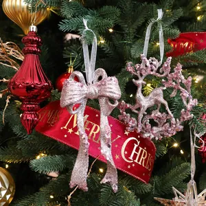 Pink glittery bow and reindeer ornaments on a Christmas tree with festive red ribbon.