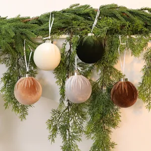 Eleganti palline di Natale in velluto appese a rami di pino per decorazioni natalizie