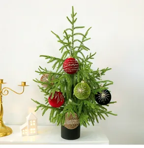 Mini sapin de Noël Norfolk décoré avec ornements en velours dans un intérieur chaleureux