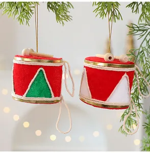 Gros plan d'ornements de Noël en forme de tambour rouge suspendus à une branche de pin
