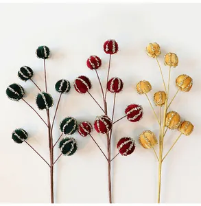 Dettaglio di rami di bacche di Natale floccati con paillettes rosse, verdi e oro.