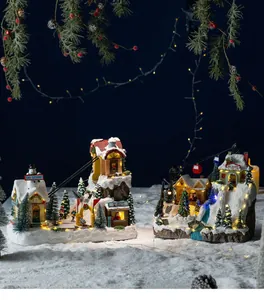 Detailed macro view of two glowing Christmas ski resort musical box scenes on artificial snow.