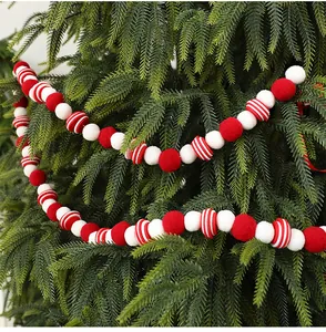 Détail d'une guirlande de boules en feutre rouge et blanc sur un sapin de Noël vert.