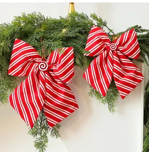 Detailopname van rood-wit gestreepte kerststrikken op een groene dennenkrans decoratie.