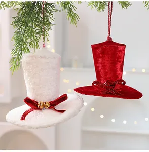 Gros plan d'ornements de chapeaux en velours rouge et blanc sur une branche de sapin