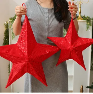 Large red sequined folding Christmas stars shown being held to demonstrate the size.