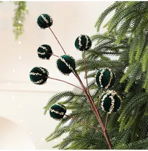 Primo piano di un ramo di bacche di Natale floccato verde con strisce di paillettes brillanti.