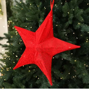Detailed view of a large red sequin folding star hanging ornament on a Christmas tree