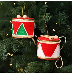 Détail de mini tambours festifs rouges et verts suspendus à un sapin de Noël illuminé.