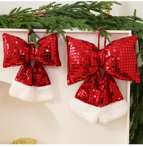 Fiocchi di Natale in paillettes rosse con bordo in pelliccia bianca su rami di pino verde.